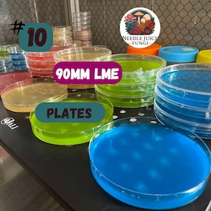 May include: A collection of clear, 90mm LME plates filled with colorful liquids, including blue, green, and yellow. The plates are stacked and arranged on a black surface. The image includes the text "#10" and "PLATES". A logo for Needle Juice Fungi is also visible.