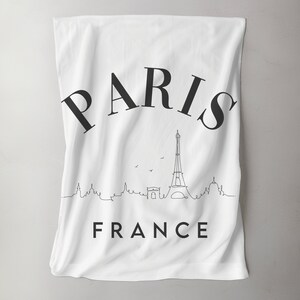 Könnte beinhalten: Weißes Küchentuch mit schwarzem Text "PARIS FRANKREICH" und einer schwarzen Strichzeichnung des Eiffelturms und anderer Pariser Sehenswürdigkeiten.