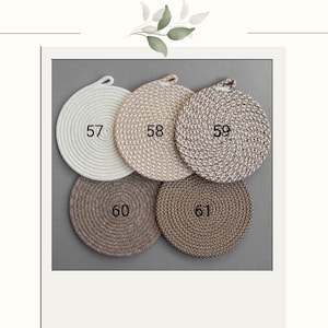 May include: A collection of five round woven coasters in various neutral colors, including white, beige, and brown. Each coaster has a loop for hanging and is labeled with a number from 57 to 61. The coasters are arranged on a gray background.