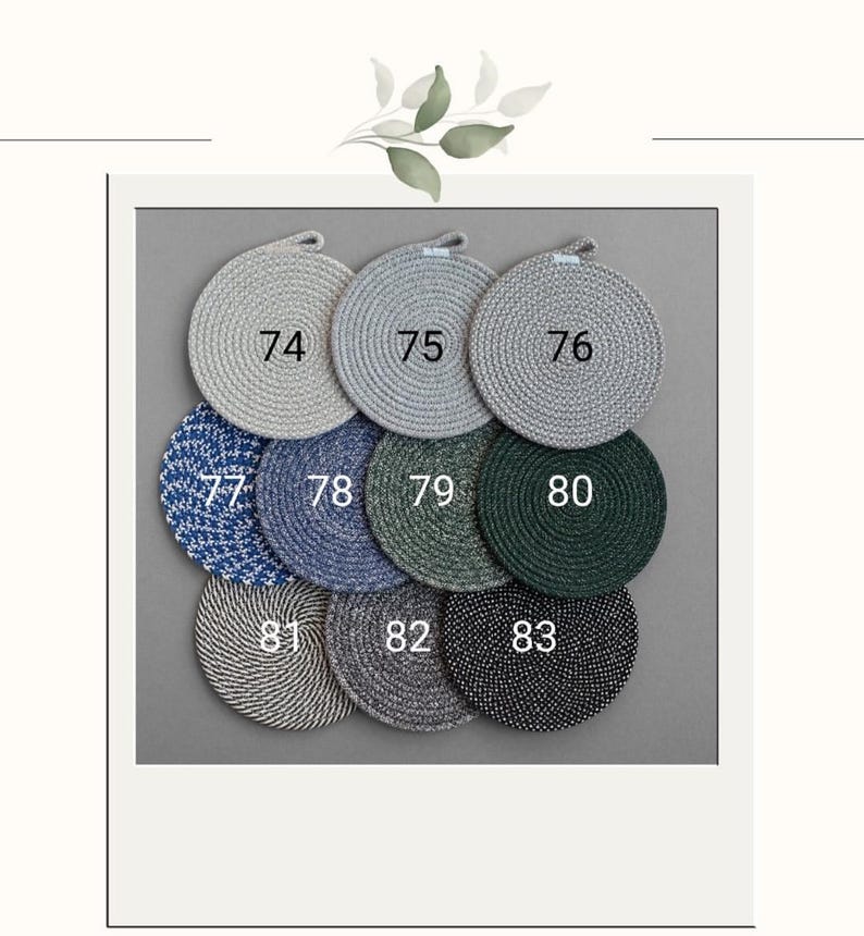May include: A collection of nine round coasters in various colors, including gray, blue, and green. Each coaster has a loop for hanging and is numbered from 74 to 83. The coasters are arranged on a gray background.