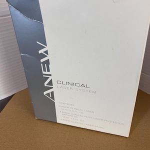 May include: A white and gray box with the text "ANEW CLINICAL LASER SYSTEM." The box lists contents including a 15 ml ANEW CLINICAL LASER, a 45 ml ANEW CLINICAL POST-LASER PROTECTOR, and a laser stand.