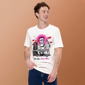 Op de afbeelding: Een wit T-shirt met korte mouwen en een grafische illustratie van een personage met meerdere armen dat aan een computerbureau werkt met een brandende servertoren. Het ontwerp bevat roze accenten, verwarde kabels en de tekst DevOps GOD MOE.
