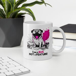 May include: A white ceramic mug featuring a cartoon illustration of a pug with a pink tongue and a pink cloud behind it. The design includes scattered items like a shoe and a pillow, with the text "I AM A BUG, NOT A FEATURE!" printed in black and pink.
