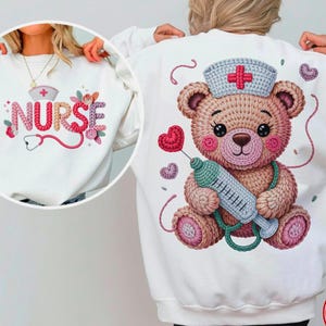 Könnte beinhalten: Weißes Sweatshirt mit einem Cartoon-Teddybär, der eine Krankenschwestermütze trägt und eine Spritze hält. Der Bär ist von Herzen umgeben. Auf der Vorderseite des Sweatshirts steht das Wort "NURSE" mit einem Stethoskop und floralen Akzenten.