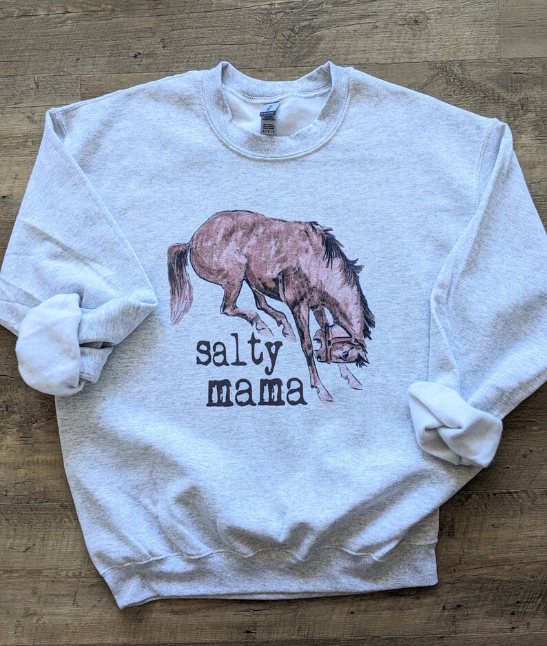 May include: A gray sweatshirt with a brown horse bucking and the text "salty mama" printed on the front.