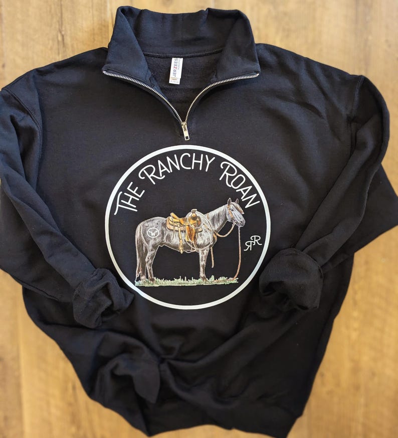 May include: Black sweatshirt with a white circle graphic featuring a horse with a saddle and the text "The Ranchy Roan" in a white circle.