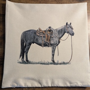 May include: A grey horse with a brown saddle and a rope halter stands on a beige background. The horse is facing the right side of the image.