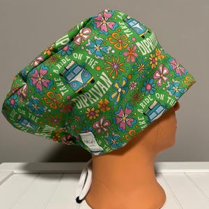 May include: Green patterned scrub cap with a floral and van design. The cap features the text "Take a ride on the Diprivan". The cap has a white drawstring and is on an orange mannequin head.