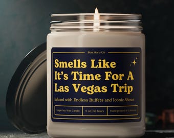 May include: A white candle jar with a blue label that reads "Smells Like It's Time For A Las Vegas Trip" and "Infused with Endless Buffets and Iconic Shows". The label also includes the text "Vegan Soy Wax Candle", "9 oz | 50 hours", and "Hand-poured in California".