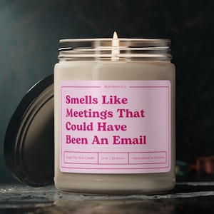 Peut inclure: Bougie parfumée dans un bocal en verre transparent avec un couvercle argenté. L'étiquette rose indique "Smells Like Meetings That Could Have Been An Email". La bougie est de 255 grammes et coulée à la main en Californie.