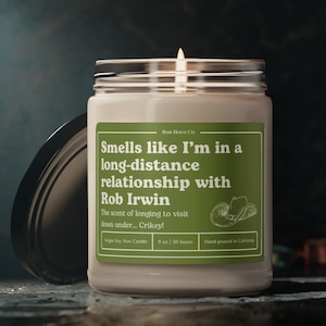 May include: A white soy wax candle with a green label that reads "Smells like I'm in a long-distance relationship with Rob Irwin. The scent of longing to visit down under... Crikey!"  The candle is 9 oz and has a burn time of 50 hours. It is hand-poured in California.