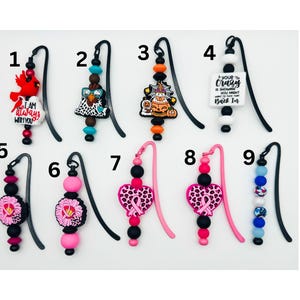May include: A collection of nine decorative bookmarks. Each bookmark features a unique charm, including a cardinal, a chicken, a jack-o'-lantern, and a block with the text "Your crazy is showing you might want to tuck that back in." Other charms include pink hearts and beads.