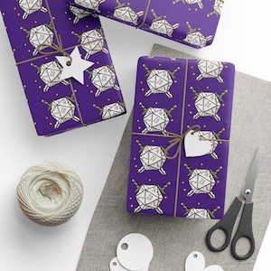 May include: Purple wrapping paper with a repeating pattern of white dice, swords, and stars. The wrapped gifts are tied with twine and have white tags. A ball of twine, scissors, and blank tags are also visible.