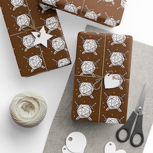 May include: Brown wrapping paper with a white D20 dice and sword pattern. Several wrapped gifts are tied with twine and adorned with star-shaped and heart-shaped tags. A ball of twine and scissors are also visible.