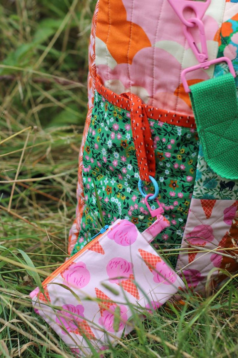 Op de afbeelding: Een kleurrijke gewatteerde tote bag met een bijpassend klein etui met ritssluiting. De tas heeft bloemen- en abstracte patronen in roze, oranje en groen. Het etui heeft een roze ijsje-ontwerp.