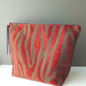 May include: A red and brown zippered pouch with a zebra print pattern.