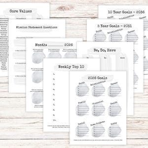 Op de afbeelding: Een verzameling witte papieren vellen met verschillende tekstkoppen, waaronder "Kernwaarden", "Missie Statement Vragen" en "2026 Doelen". De vellen hebben een minimalistisch ontwerp met grijze aquarelaccenten en zijn gerangschikt op een licht houten oppervlak.
