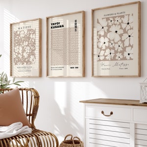Op de afbeelding: Drie ingelijste kunstprints met een beige achtergrond en witte ontwerpen. De prints tonen abstracte patronen en bloemmotieven. De prints zijn getiteld "Matisse", "Yayoi Kusama" en "Bloemen & Planten".