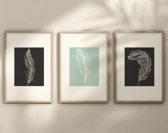 May include: Three framed prints with white feather illustrations on different colored backgrounds. The left print has a black background, the middle print has a light green background, and the right print has a black background.
