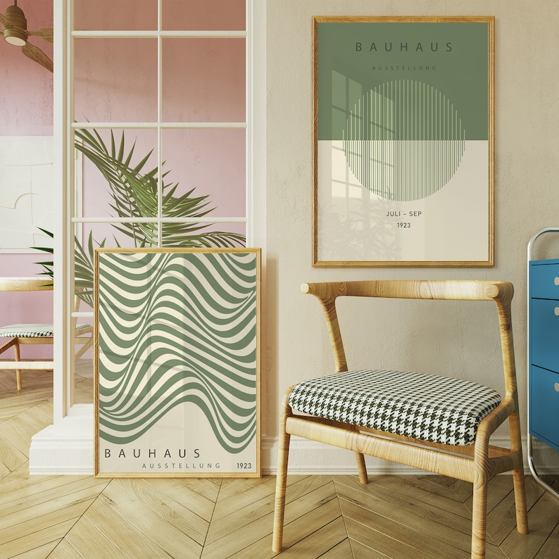 May include: Two framed posters with a green and white geometric design. The posters are hanging on a white wall. The poster on the left has the text "BAUHHAUS AUSSTELLUNG 1923". The poster on the right has the text "BAUHHAUS AUSSTELLUNG JULI-SEP 1923".