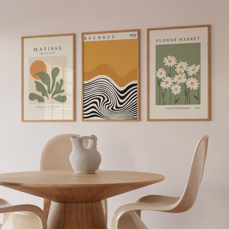 May include: Three framed art prints with minimalist designs. The left print features a green plant with a yellow sun, the middle print has a black and white wavy design with a yellow background, and the right print has white daisies on a green background.