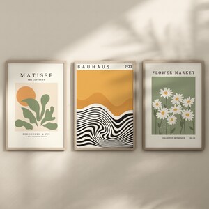May include: Three framed art prints with minimalist designs. The left print features a green plant with a yellow sun, titled "Matisse, The Cut-Outs". The middle print features black and white wavy lines with a yellow background, titled "Bauhaus, 1923". The right print features white daisies on a green background, titled "Flower Market, Collection Botanique, No:10".
