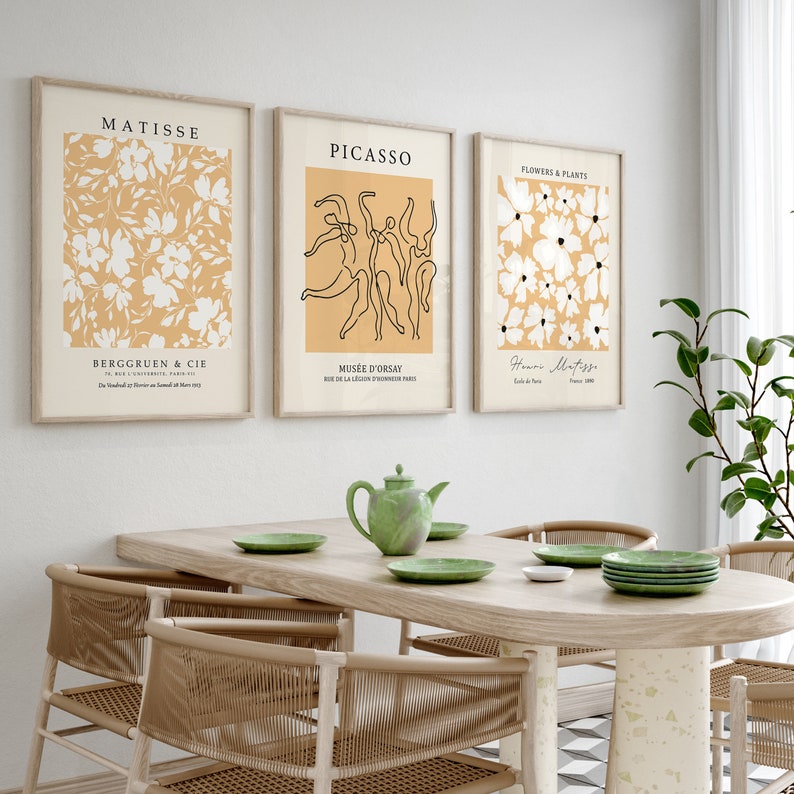 K&ouml;nnte beinhalten: Drei minimalistische Kunstdrucke mit gelbem Hintergrund und schwarzen Linienzeichnungen. Die Drucke sind mit "Matisse", "Picasso" und "Blumen & Pflanzen" betitelt.