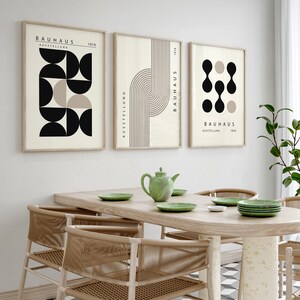 May include: Three framed prints with geometric shapes in black, white, and beige. The prints have the text "Bauhaus Ausstellung 1919" on them.