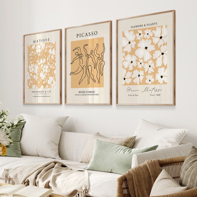 K&ouml;nnte beinhalten: Drei minimalistische Kunstdrucke mit beigefarbenem Hintergrund und wei&szlig;en Akzenten. Der linke Druck zeigt ein Blumenmuster und den Text "MATISSE" und "BERGGRUEN & CIE". Der mittlere Druck zeigt eine Linienzeichnung von T&auml;nzern und den Text "PICASSO" und "MUS&Eacute;E D'ORSAY". Der rechte Druck zeigt ein Blumenmuster und den Text "FLOWERS & PLANTS" und "Henri Matisse".