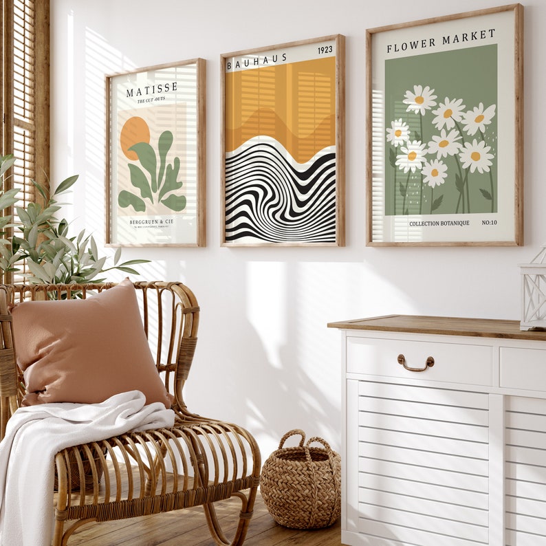 May include: Three framed art prints with a minimalist design. The left print features a green plant with a yellow sun in the background. The middle print features black and white abstract lines. The right print features white daisies on a green background. The prints are labeled "Matisse", "Bauhaus 1923", and "Flower Market".