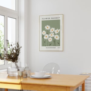 May include: A framed print with a green background and white daisies. The print has the text "FLOWER MARKET" at the top and "COLLECTION BOTANIQUE NO.10" at the bottom.