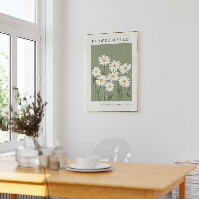 May include: A framed print with a green background and white daisies. The print has the text "FLOWER MARKET" at the top and "COLLECTION BOTANIQUE NO.10" at the bottom.