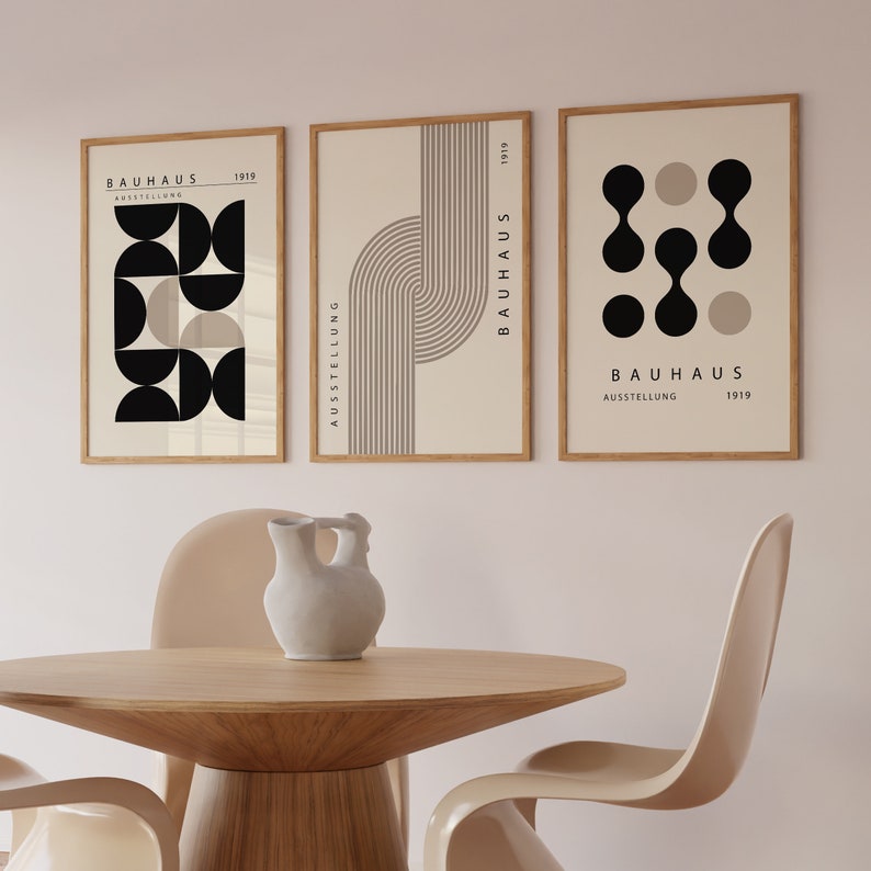 May include: Three framed prints with a minimalist design featuring black and beige geometric shapes and the text "BAUHAUS AUSSTELLUNG 1919".