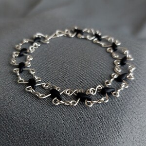 The geometric silver plated wire bracelet with black tear-shaped beads.