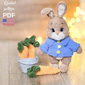 May include: Crochet pattern PDF for a brown bunny wearing a blue shirt and holding a carrot. The bunny is sitting on a wooden surface with a basket of carrots in the background.