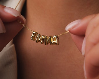 May include: A gold necklace with the name "EMMA" spelled out in individual letters.