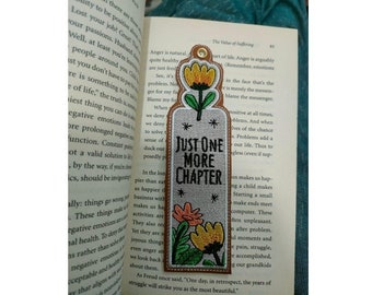 May include: A brown bookmark with colorful embroidered flowers and the text "Just One More Chapter".
