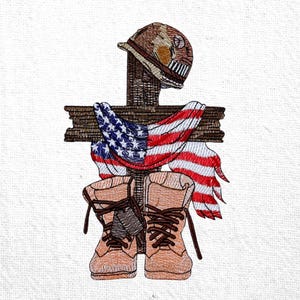 May include: Embroidered design featuring a wooden cross with a military helmet, an American flag draped over it, and a pair of combat boots. The design uses shades of brown, red, white, and blue, creating a patriotic and memorial theme.