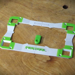 Può includere: Un telaio in plastica bianco e verde con il testo "Festool" e "KANNWOOD" stampato su di esso. Il telaio è progettato per contenere uno strumento.