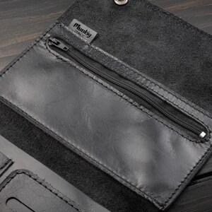 May include: Black leather wallet with a zippered pocket and snap closures. The wallet has a textured surface and visible stitching. The brand name "Munkig ITALY" is visible on a small tag.
