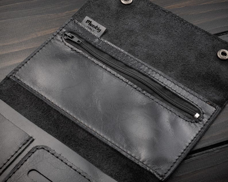 May include: Black leather wallet with a zippered pocket and snap closures. The wallet has a textured surface and visible stitching. The brand name "Munkig ITALY" is visible on a small tag.