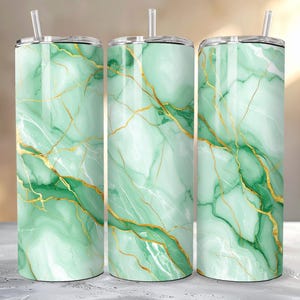 以下が含まれることがあります： 蓋とストローが付いた3つのステンレス鋼タンブラー。タンブラーは、金色の静脈を持つ緑の大理石のデザインが特徴です。デザインは3つのタンブラーすべてで一貫しており、まとまりのあるセットになっています。タンブラーは円筒形で、断熱されているようです。