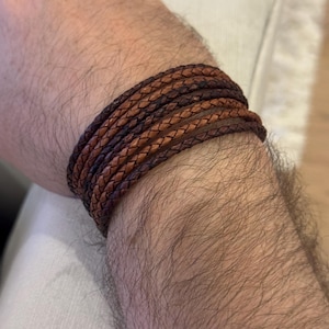 K&ouml;nnte beinhalten: Geflochtenes Lederarmband in Braun- und Beiget&ouml;nen. Das Armband ist mehrfach um das Handgelenk gewickelt und zeigt das aufwendige Webdesign. Das Leder hat eine nat&uuml;rliche, leicht abgenutzte Oberfl&auml;che. Umfang ca. 20 cm.