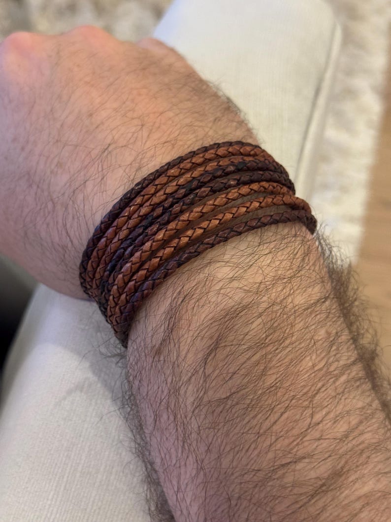 K&ouml;nnte beinhalten: Geflochtenes Lederarmband in Braun- und Beiget&ouml;nen. Das Armband ist mehrfach um das Handgelenk gewickelt und zeigt das aufwendige Webdesign. Das Leder hat eine nat&uuml;rliche, leicht abgenutzte Oberfl&auml;che. Umfang ca. 20 cm.