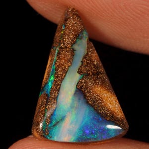 Könnte beinhalten: Ein dreieckiger Boulder-Opal-Edelstein mit einer dunkelbraunen, texturierten Eisensteinmatrix und einer lebendigen, irisierenden Ader aus Blau und Grün, die vertikal durch die Mitte der polierten Steinoberfläche verläuft.