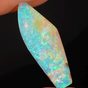 May include: A marquise-shaped opal gemstone displaying a vibrant play-of-colour with iridescent flashes of neon blue, bright green, and soft orange against a translucent, milky white base. The stone features a smooth, polished surface.