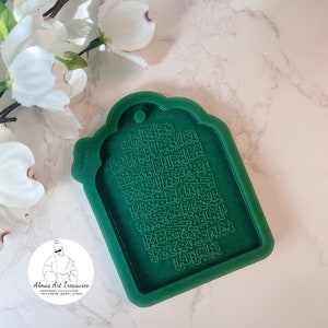 May include: Green silicone mold for making a decorative tag with Arabic calligraphy. The mold has a rounded top and a rectangular shape. The calligraphy is raised and detailed.