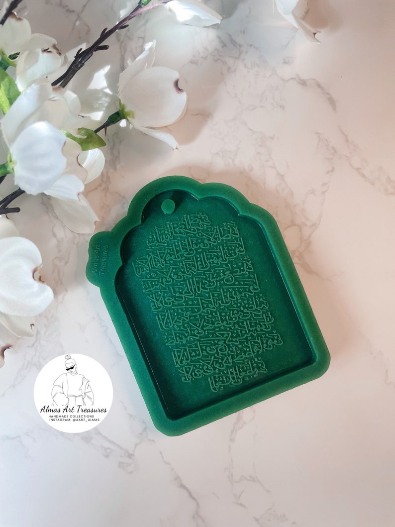 May include: Green silicone mold for making a decorative tag with Arabic calligraphy. The mold has a rounded top and a rectangular shape. The calligraphy is raised and detailed.