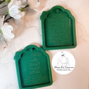 May include: Two green silicone molds for making resin crafts. The molds are shaped like a traditional Islamic archway and feature Arabic calligraphy. The text in the molds reads "Almas Art Treasures Handmade Collections Instagram: @aart_almas".