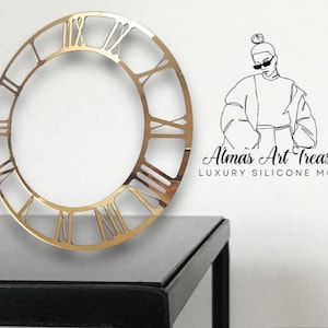 May include: A gold-coloured, open-faced clock frame with Roman numerals. The clock frame is circular and sits on a black surface. The image also includes a line drawing of a person and the text "Almas Art Treasures LUXURY SILICONE MOLD."